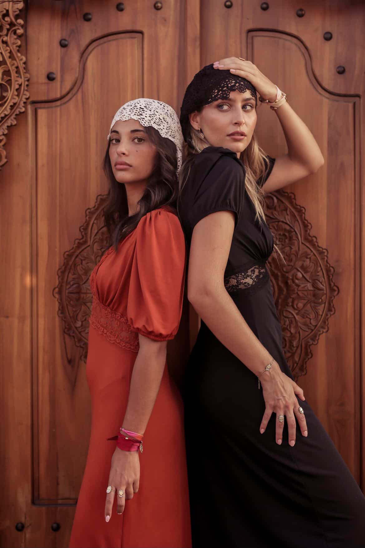 Shooting Amadrina : deux modèles portant les bijoux devant les portes en bois sculpté