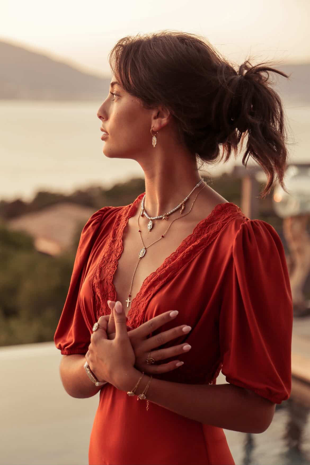 Shooting Amadrina : portrait en robe rouge avec la mer en arrière-plan à Terra di Gaya